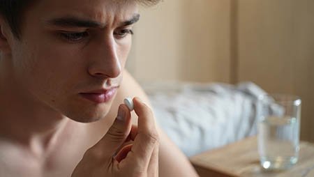 Мужчина держит в руке белую таблетку